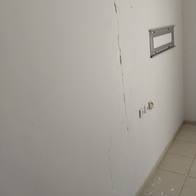 קיר עם סדק ותיקוני צבע על הרצפה