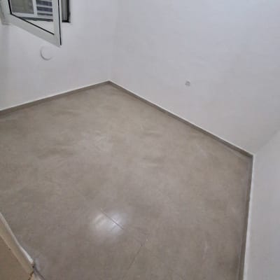 חדר ריק עם רצפת קרמיקה חדשה וקיר לבן