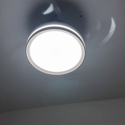 מנורת תקרה עגולה מוארת על תקרה אפורה