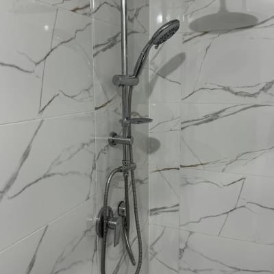 מקלחת עם ראשי מקלחת וכיורים על קיר שיש