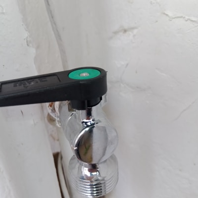 ברז מתכת עם ידית שחורה על קיר לבן