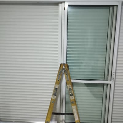 תריסים לבנים סגורים עם סולם עץ מלפנים