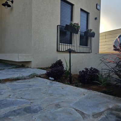 עציצים עם פרחים על אדן חלון, שביל אבן בגינה