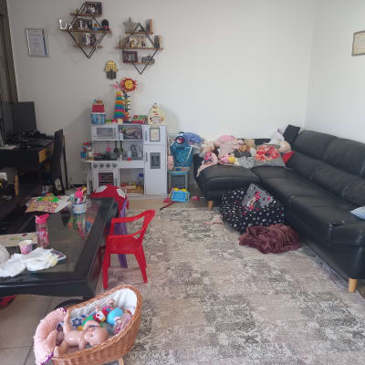 חדר מגורים עם צעצועים מפוזרים וספה שחורה