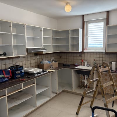 מטבח בתהליך שיפוץ עם ארונות פתוחים וסולם