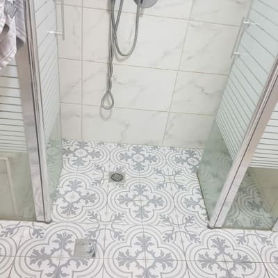 מקלחון עם דלתות זכוכית ודוש תלוי על קיר