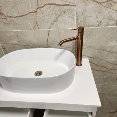 כיור וברז בחדר אמבטיה עם אריחי קיר.