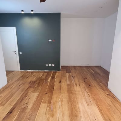 רצפת פרקט עץ בחדר עם קיר כהה ותקרה לבנה