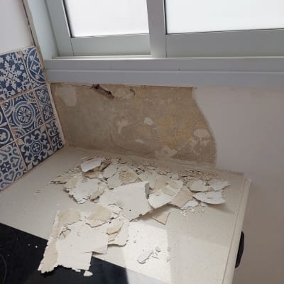 קיר מתקלף ליד חלון עם טיח מתפורר