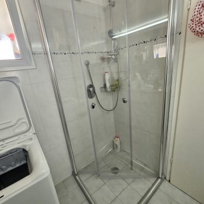 מקלחון זכוכית עם בקבוקי שמפו וסבון