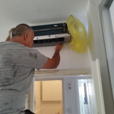 אדם מתקן מזגן עם שקית צהובה לידו