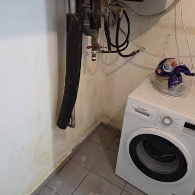 מכונת כביסה עם צינורות וחיבורים על הקיר