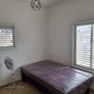 חדר צבוע עם מיטה מכוסה בניילון ומאוורר