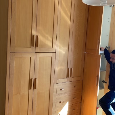 אדם פותח דלת ארון עץ בחדר שינה מואר