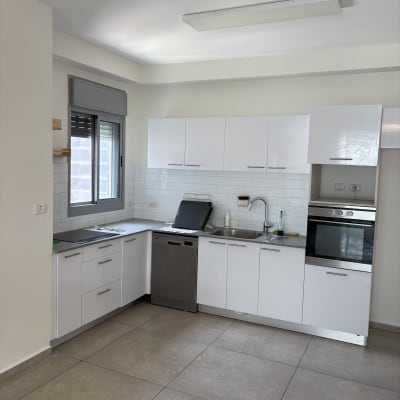מטבח מודרני עם ארונות לבנים ורצפת אריחים
