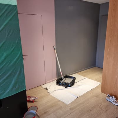 ציוד צביעה עם גליל צבע על קיר ורוד ואפור