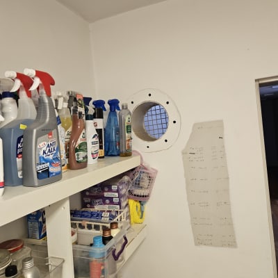 מדף עם חומרי ניקוי וחור עגול בקיר