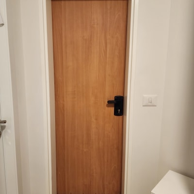 דלת עץ עם ידית שחורה במסגרת לבנה