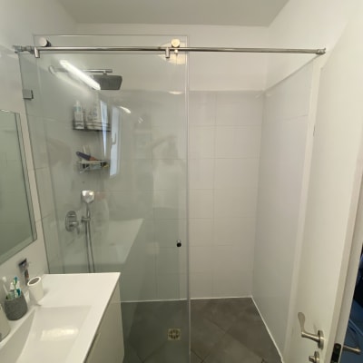 מקלחון זכוכית עם כיור ומראה בחדר אמבטיה מודרני