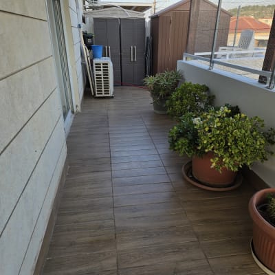 מרפסת עם רצפת עץ, עציצים ויחידת מיזוג אוויר