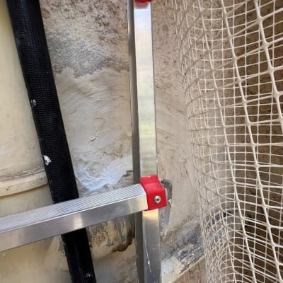 סולם מתכת ליד קיר עם רשת לבנה