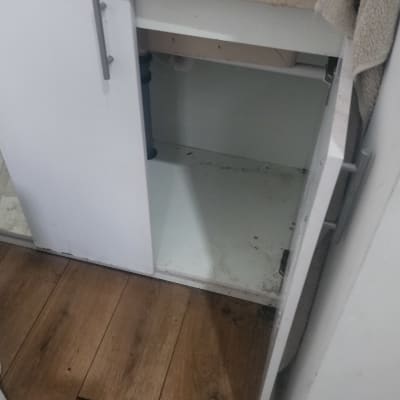 ארון מטבח פתוח עם סימני לכלוך מתחת לכיור