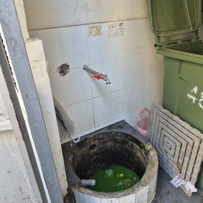 ברז מים ליד פתח ביוב עם מים ירוקים