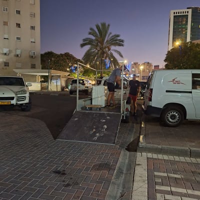 אנשים מעמיסים ציוד על רכב מסחרי בלילה