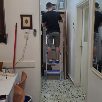 חשמלאי עומד על סולם ומתקן לוח חשמל