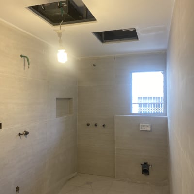 חדר אמבטיה בשיפוץ עם חורים בתקרה וצנרת חשופה