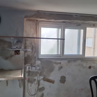 קיר מתקלף עם חלון, שקעי חשמל וחוטים חשופים