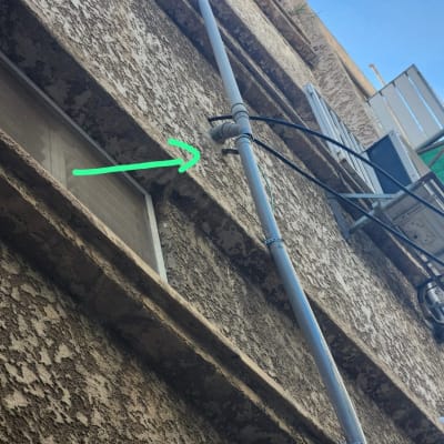 צינור חיצוני על קיר בניין עם חץ ירוק