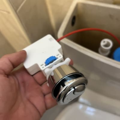 יד מחזיקה חלק מתכת של מיכל הדחה בשירותים