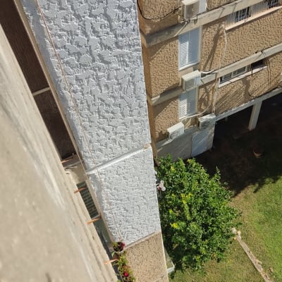 בניין עם קיר מחוספס וצמחייה למטה