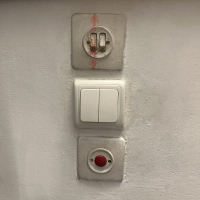 מתג חשמלי כפול וכפתור אדום על קיר