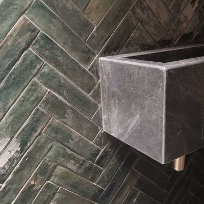 כיור אבן וברז זהב על רקע אריחים ירוקים