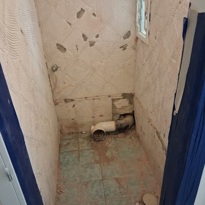 חדר אמבטיה בתהליך שיפוץ עם קירות חשופים וצנרת גלויה