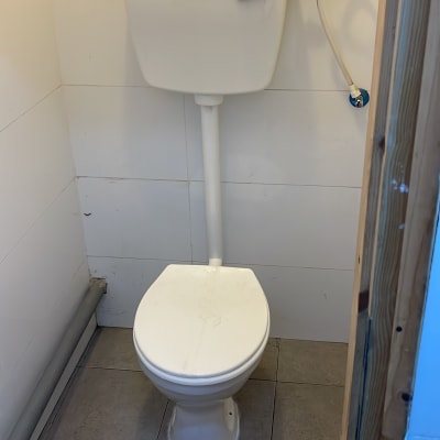 אסלה עם מיכל הדחה וצינור מים מחובר