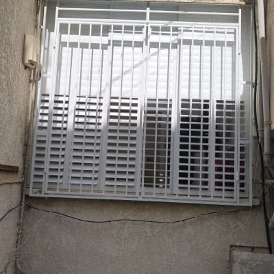 סורגים לבנים מותקנים על חלון קיר חיצוני