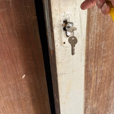 יד מחזיקה מפתח בדלת עץ עם מנעול