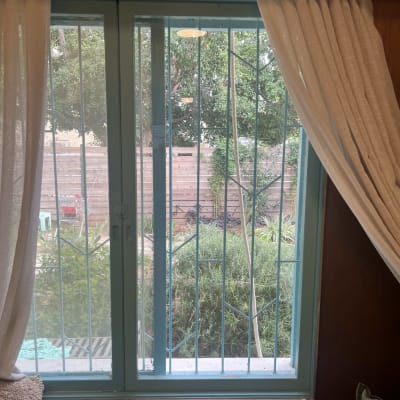 חלון זכוכית עם סורגים ווילונות לבנים