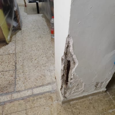 קיר עם טיח מתקלף וחשיפת ברזל בניין