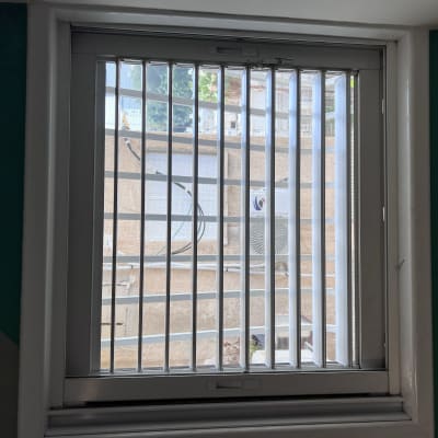 תריסים לבנים אנכיים על חלון עם מסגרת לבנה