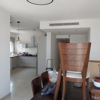 כיסאות עץ על שולחן בחדר אוכל עם מטבח ברקע