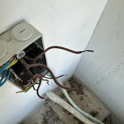 חוטי חשמל חשופים יוצאים מקופסת חשמל בקיר