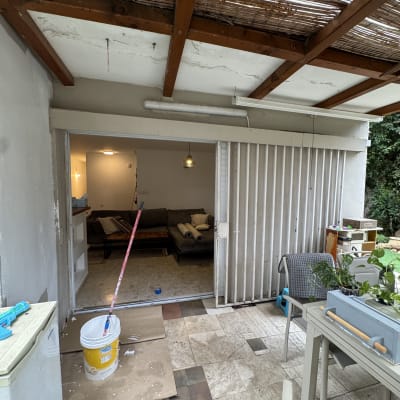 דלי צבע ומברשת באזור חיצוני עם גג עץ