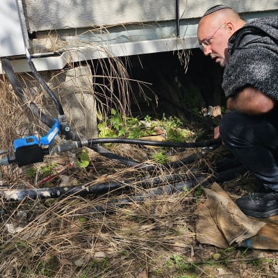 אדם בודק צינור ליד מבנה