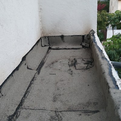 איטום גג עם זפת שחורה על משטח בטון