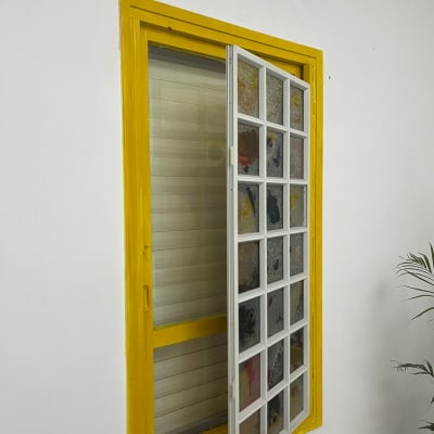 חלון עם מסגרת צהובה וקיר לבן