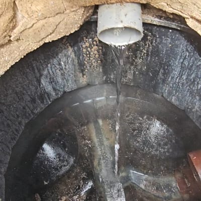 מים זורמים מצינור לתוך בור ניקוז